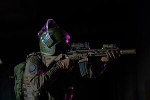 armée soldat dans combat uniformes avec un agression fusil et combat casque nuit mission foncé Contexte. bleu et violet gel lumière effet. photo