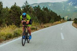 plein longueur portrait de un actif triathlète dans tenue de sport et avec une protecteur casque équitation une vélo. sélectif concentrer photo