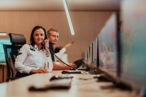 femelle Sécurité garde opérateur parlant sur le téléphone tandis que travail à poste de travail avec plusieurs affiche Sécurité gardes travail sur plusieurs moniteurs photo