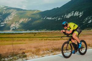 plein longueur portrait de un actif triathlète dans tenue de sport et avec une protecteur casque équitation une vélo. sélectif concentrer photo