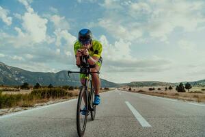 plein longueur portrait de un actif triathlète dans tenue de sport et avec une protecteur casque équitation une vélo. sélectif concentrer photo