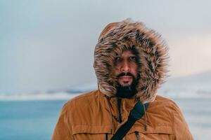 photo du visage photo de une homme dans une du froid neigeux zone portant une épais marron hiver veste et gants. la vie dans du froid Régions de le pays.