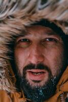 photo du visage photo de une homme dans une du froid neigeux zone portant une épais marron hiver veste et gants. la vie dans du froid Régions de le pays.