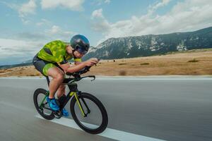 plein longueur portrait de un actif triathlète dans tenue de sport et avec une protecteur casque équitation une vélo. sélectif concentrer photo