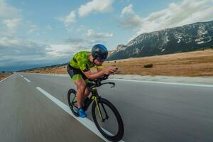 plein longueur portrait de un actif triathlète dans tenue de sport et avec une protecteur casque équitation une vélo. sélectif concentrer photo