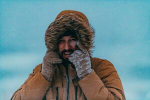 photo du visage photo de une homme dans une du froid neigeux zone portant une épais marron hiver veste et gants. la vie dans du froid Régions de le pays.