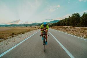 plein longueur portrait de un actif triathlète dans tenue de sport et avec une protecteur casque équitation une vélo. sélectif concentrer photo