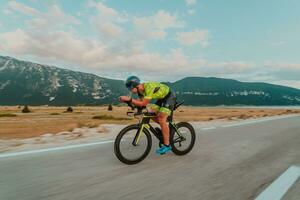 plein longueur portrait de un actif triathlète dans tenue de sport et avec une protecteur casque équitation une vélo. sélectif concentrer photo