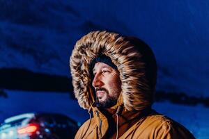 tête coup de une homme dans une du froid neigeux zone portant une épais marron hiver veste, neige des lunettes de protection et gants sur une du froid scandinave nuit. la vie dans le du froid Régions de le pays. photo