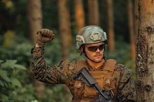 moderne guerre soldat officier est montrant tactique main signaux à silencieusement donner ordres et alertes pour équipe équipe forêt environnement photo