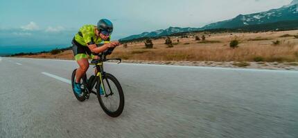 plein longueur portrait de un actif triathlète dans tenue de sport et avec une protecteur casque équitation une vélo. sélectif concentrer photo