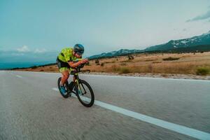 plein longueur portrait de un actif triathlète dans tenue de sport et avec une protecteur casque équitation une vélo. sélectif concentrer photo