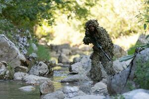 une militaire homme ou airsoft joueur dans une camouflage costume se faufiler le rivière et objectifs de une tireur d'élite fusil à le côté ou à cible. photo