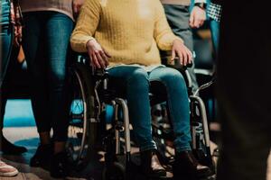 proche en haut photo de une femme avec une invalidité séance dans une fauteuil roulant dans le Bureau