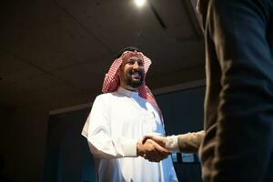 un personnes âgées arabe homme tremblement mains avec une homme d'affaire et fin une affaires réunion avec réussi affaires offres photo