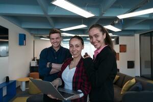 une groupe de Jeune enthousiaste Jeune affaires gens dans moderne bureau. une affaires femme avec une portable dans sa main, dans le Contexte une collègues avec franchi bras photo