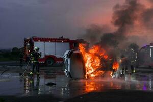 sapeurs pompiers bats toi le Feu flamme à contrôle Feu ne pas à diffusion dehors. sapeur pompier industriel et Publique sécurité concept. circulation ou voiture accident porter secours et Aidez-moi action. photo