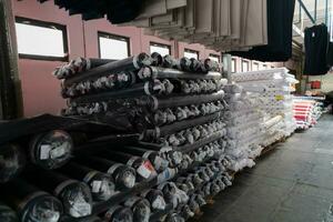 intérieur de un industriel entrepôt avec en tissu Rouleaux échantillons. petit affaires textile coloré entrepôt. photo