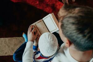 prière musulmane père et fils dans la mosquée priant et lisant le livre de houx coran ensemble concept d'éducation islamique photo