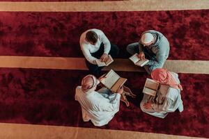 une groupe de les musulmans en train de lire le saint livre de le coran dans une moderne mosquée pendant le musulman vacances de Ramadan photo