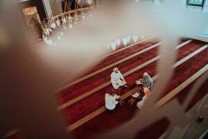 une groupe de les musulmans en train de lire le saint livre de le coran dans une moderne mosquée pendant le musulman vacances de Ramadan photo