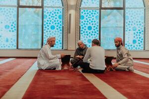 une groupe de les musulmans en train de lire le saint livre de le coran dans une moderne mosquée pendant le musulman vacances de Ramadan photo