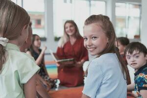 en train de lire temps dans un élémentaire école ou Jardin d'enfants, une prof lit une livre à les enfants dans un élémentaire école ou Jardin d'enfants. le concept de préscolaire éducation. sélectif concentrer photo