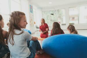 en train de lire temps dans un élémentaire école ou Jardin d'enfants, une prof lit une livre à les enfants dans un élémentaire école ou Jardin d'enfants. le concept de préscolaire éducation. sélectif concentrer photo