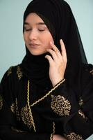 magnifique musulman femme dans à la mode robe avec hijab isolé sur moderne cyan Contexte représentant concept de moderne Islam et Ramadan kareem photo