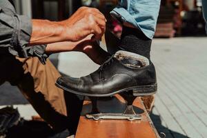 un vieux homme main polissage et La peinture une noir chaussure à rue photo