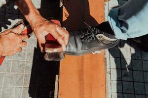 un vieux homme main polissage et La peinture une noir chaussure à rue photo