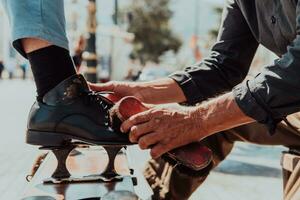 un vieux homme main polissage et La peinture une noir chaussure à rue photo