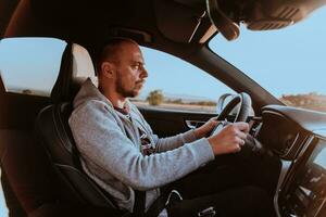 une homme avec une des lunettes de soleil conduite une voiture à le coucher du soleil. le concept de voiture Voyage photo