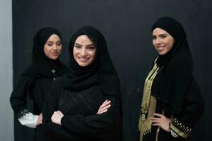 groupe portrait de magnifique musulman femmes dans une à la mode robe avec hijab isolé sur noir Contexte photo