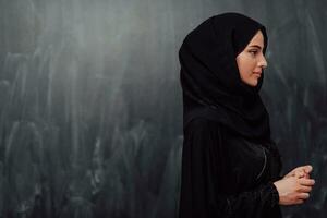 portrait de magnifique musulman femme dans à la mode robe avec hijab dans de face de noir tableau noir représentant moderne Islam mode et Ramadan kareem concept photo
