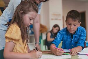 Créatif des gamins pendant un art classe dans une garderie centre ou élémentaire école salle de cours dessin avec femelle professeur. photo