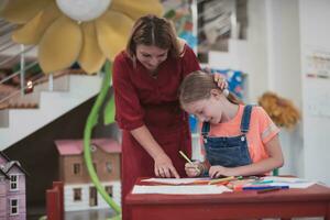 Créatif des gamins pendant un art classe dans une garderie centre ou élémentaire école salle de cours dessin avec femelle professeur. photo