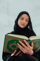 Jeune traditionnel musulman femme en train de lire coran sur le canapé avant iftar dîner pendant une Ramadan le banquet à Accueil photo