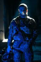 armée soldat dans combat uniformes avec un agression fusil et combat casque nuit mission foncé Contexte. bleu et violet gel lumière effet. photo