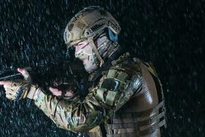 armée soldat dans combat uniformes avec un agression fusil, assiette transporteur et combat casque Aller sur une dangereux mission sur une pluvieux nuit. photo