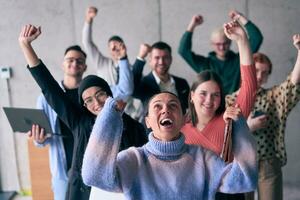 une diverse groupe de réussi les hommes d'affaires soulève leur mains dans le air, symbolisant réalisation, accomplissement, et le accomplissement de buts, exsudant confiance, unité, et fête de leur collectif succès. photo