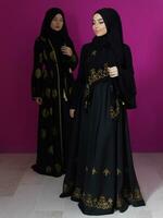 deux magnifique musulman femme dans à la mode robe avec hijab isolé sur moderne rose Contexte représentant concept de moderne Islam et Ramadan kareem photo