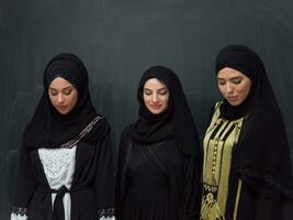 groupe portrait de magnifique musulman femmes dans une à la mode robe avec hijab isolé sur noir Contexte photo
