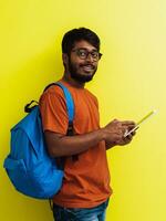 Indien étudiant avec bleu sac à dos, des lunettes et carnet posant sur gris et vert Contexte. le concept de éducation et scolarité. temps à aller retour à école photo