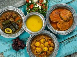 eid mubarak traditionnel Ramadan iftar dîner. assorti savoureux nourriture dans authentique rustique vaisselle sur en bois bleu Contexte. turc bosniaque nourriture Viande kebab, Pita, sarma, klepe, sogan dolma. photo