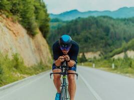 plein longueur portrait de un actif triathlète dans tenue de sport et avec une protecteur casque équitation une vélo. sélectif concentrer photo