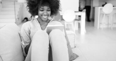 femme afro-américaine à la maison à l'aide d'une tablette numérique photo