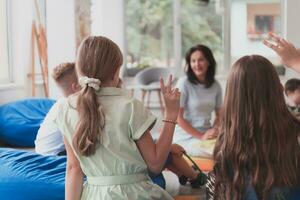 en train de lire temps dans un élémentaire école ou Jardin d'enfants, une prof lit une livre à les enfants dans un élémentaire école ou Jardin d'enfants. le concept de préscolaire éducation. sélectif concentrer photo