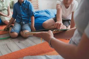 en train de lire temps dans un élémentaire école ou Jardin d'enfants, une prof lit une livre à les enfants dans un élémentaire école ou Jardin d'enfants. le concept de préscolaire éducation. sélectif concentrer photo