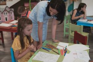 Créatif des gamins pendant un art classe dans une garderie centre ou élémentaire école salle de cours dessin avec femelle professeur. photo